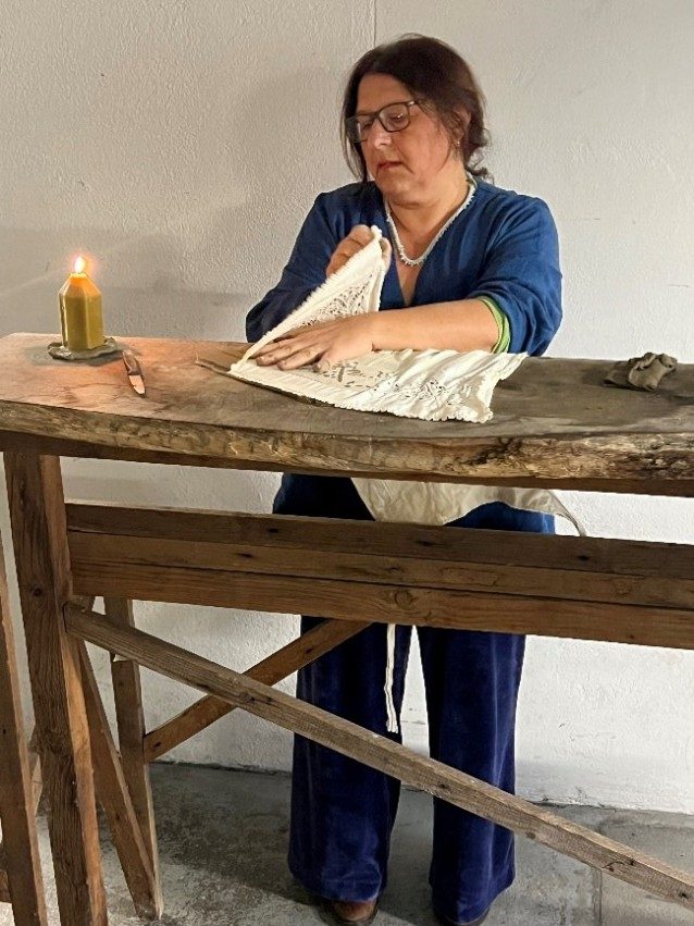 Carmen Indergand-Bira arbeitet bei Kerzenlicht an einem Holztisch